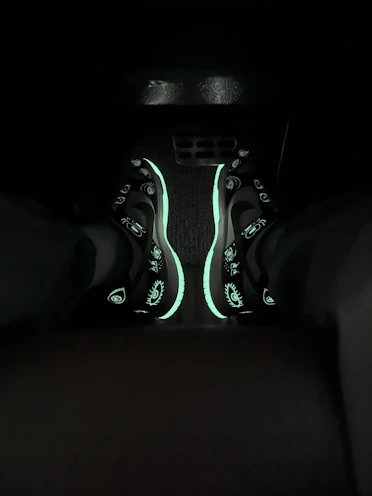 A sleek pair of streetwear sneakers glowing subtly under neon lights.