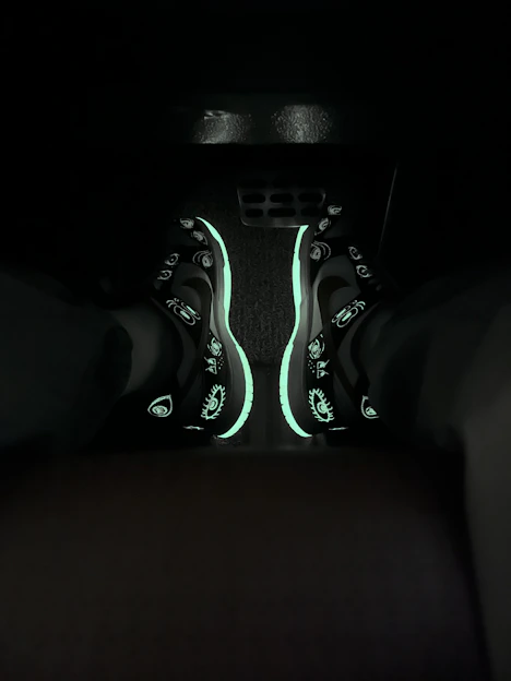Close-up of a sleek black and neon-accented sneaker glowing softly against a dark background
