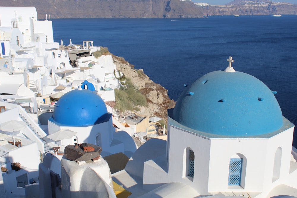 a white building with blue domes by the water
