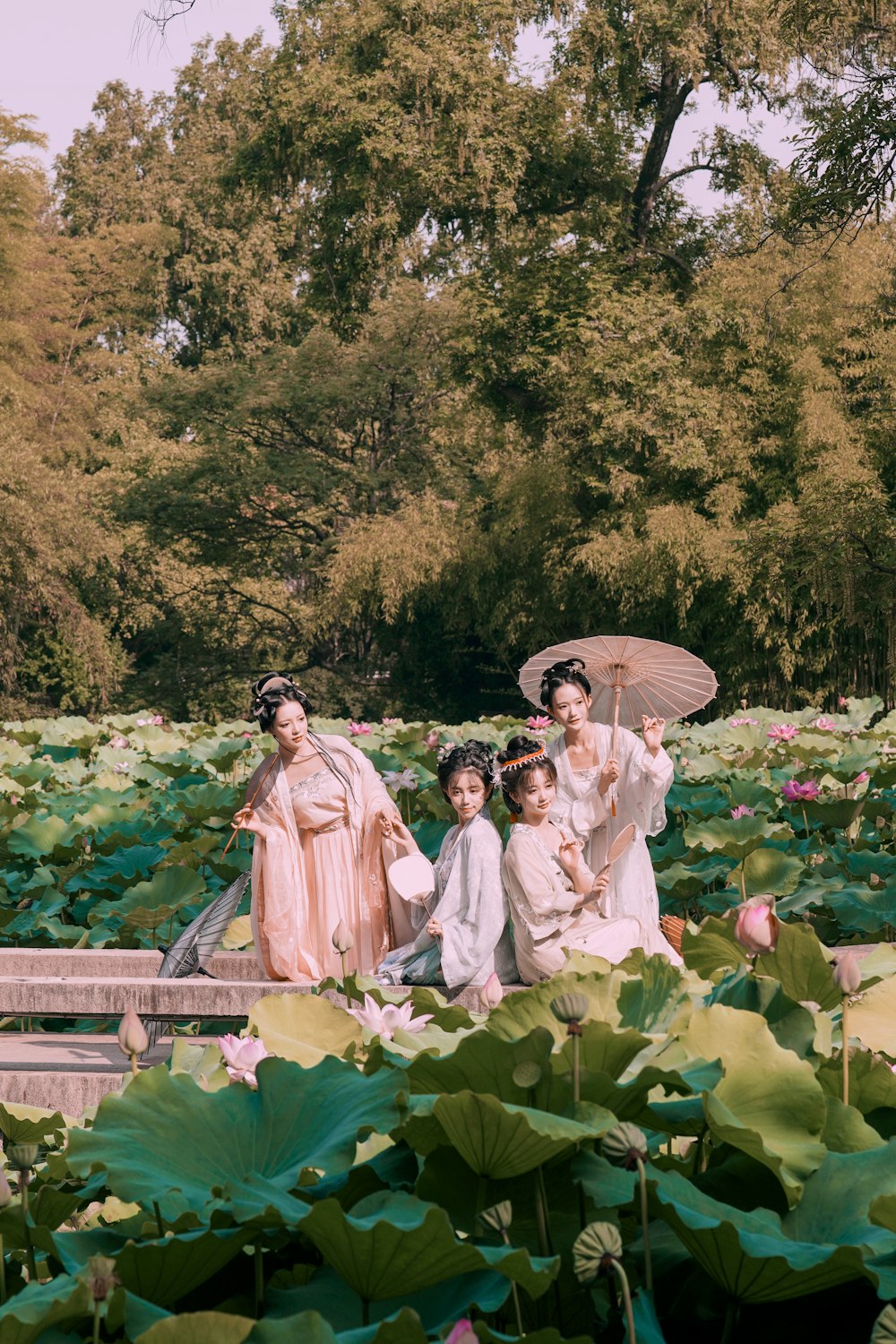 a group of women in dresses standing under an umbrella