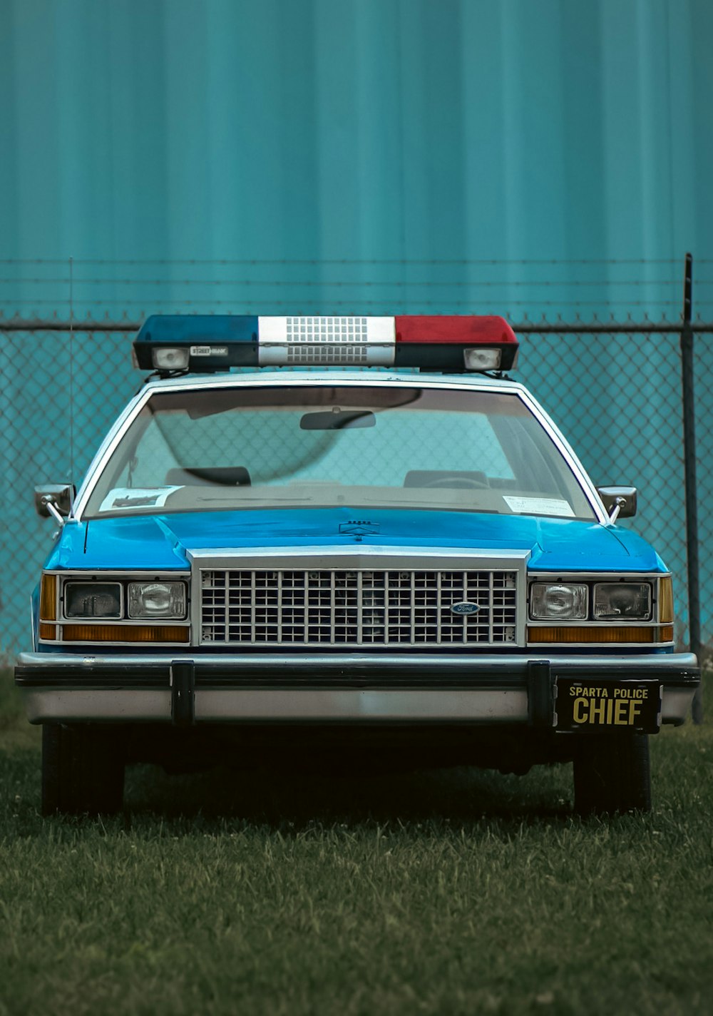 a police car parked in front of a fence