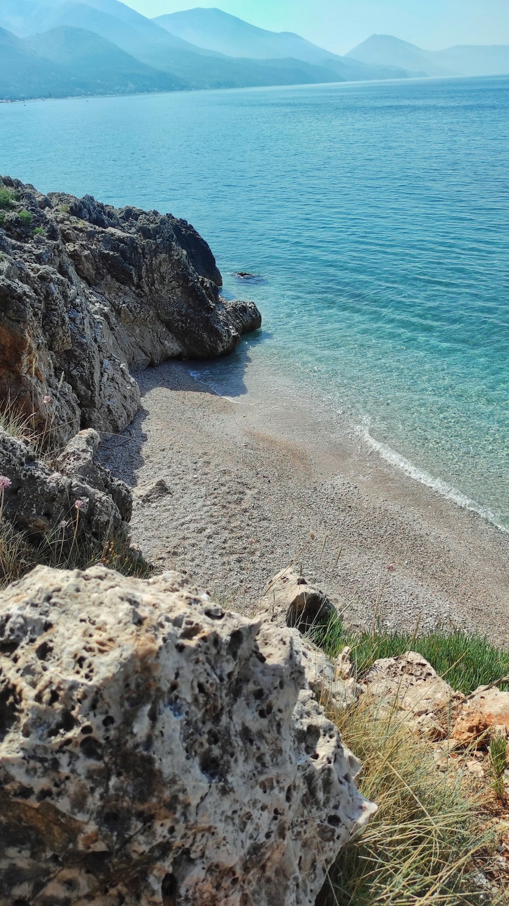 a rocky beach with a body of water in the background