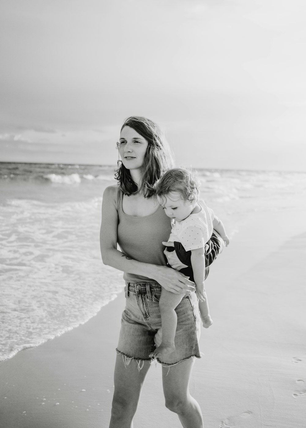 Una persona sosteniendo a un bebé en una playa