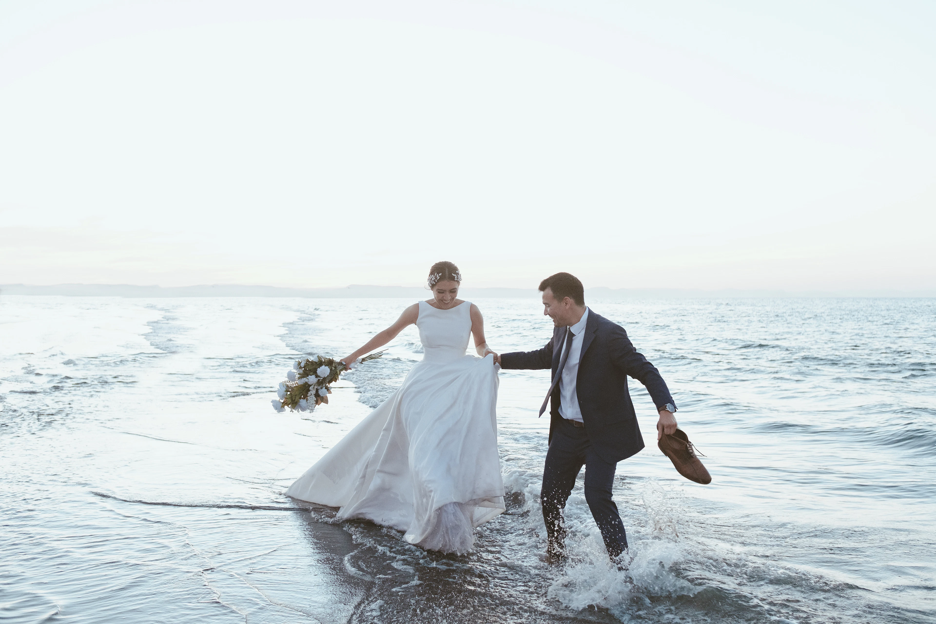 Léa et Hugo courent pieds nus dans les vagues, au petit matin