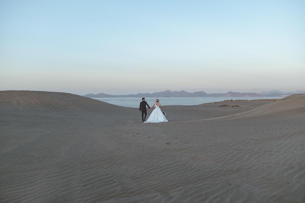 a bride and groom walking in the desert