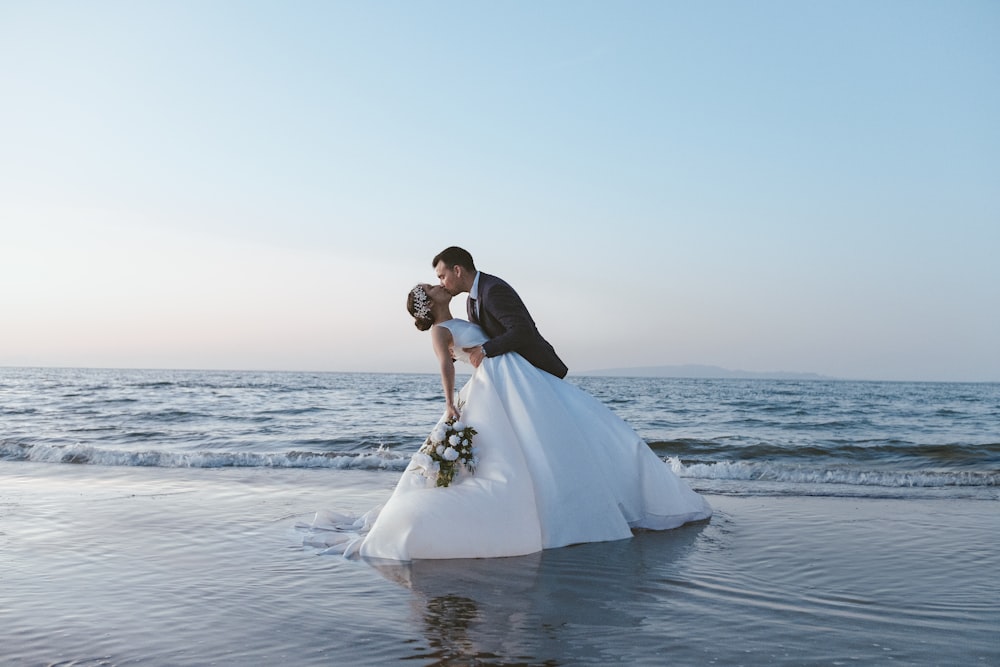 a man and woman in wedding attire on a beach