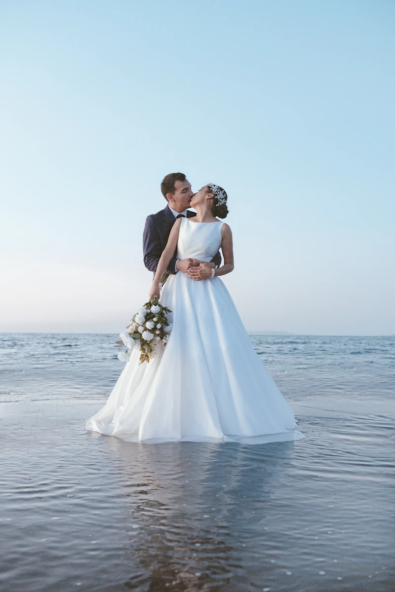 Couple kissing in the ocean after their beach wedding
