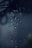 Droplets of water are suspended in mid-air against a dark background, with a focus on their glistening surfaces. The drops appear as if captured in motion, emphasizing their clarity and the subtle play of light.