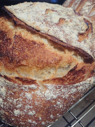A close-up of a freshly baked artisan sourdough loaf with a golden crust resting on a rustic wooden board.