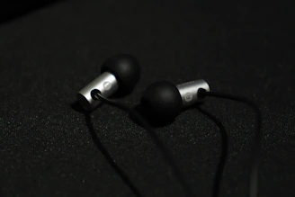 Sleek TC4 titanium alloy shell of the in-ear monitor resting on a deep black surface with subtle gold accents.
