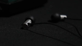 Close-up of a sleek black and blue in-ear monitor resting on a dark reflective surface.