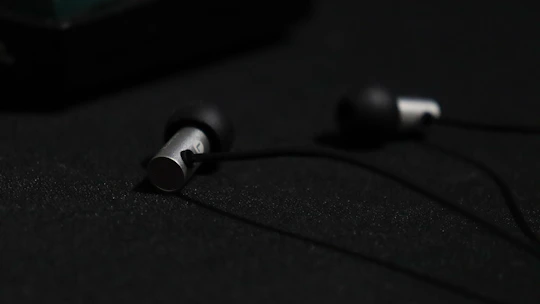Close-up of a sleek black and blue in-ear monitor resting on a dark reflective surface.