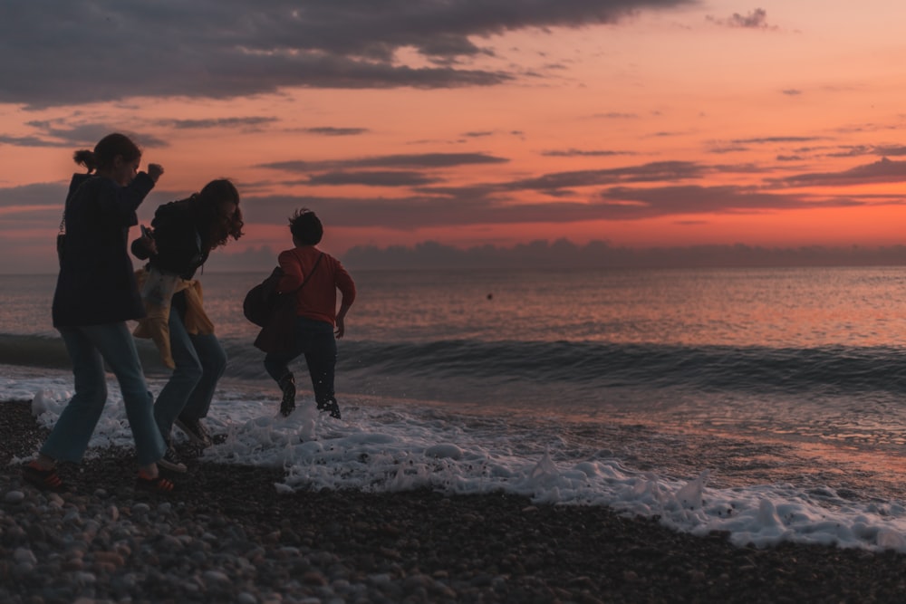 a group of people walking on a beach at sunset