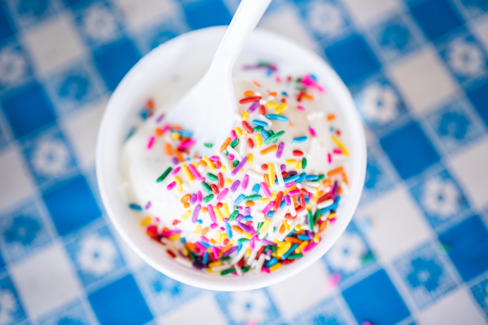 a cup of yogurt with sprinkles and a spoon