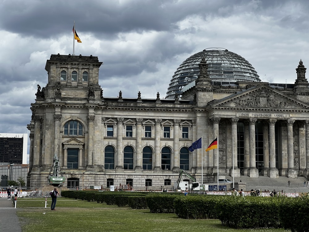 a large building with a dome and flags in front of it with Reichstag building in the background