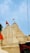 The image features a traditional Indian temple with intricately carved spires and domes, adorned with orange flags. The temple is painted in a light cream color against a clear blue sky.
