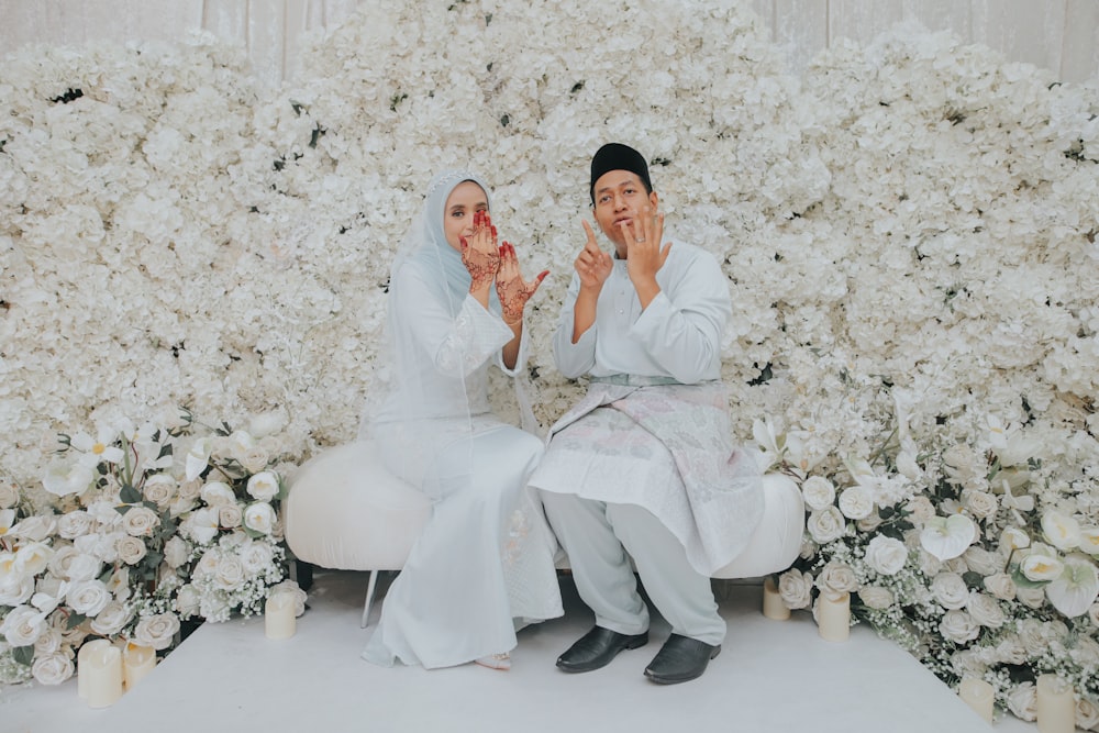 a man and woman sitting in a chair with flowers in the background