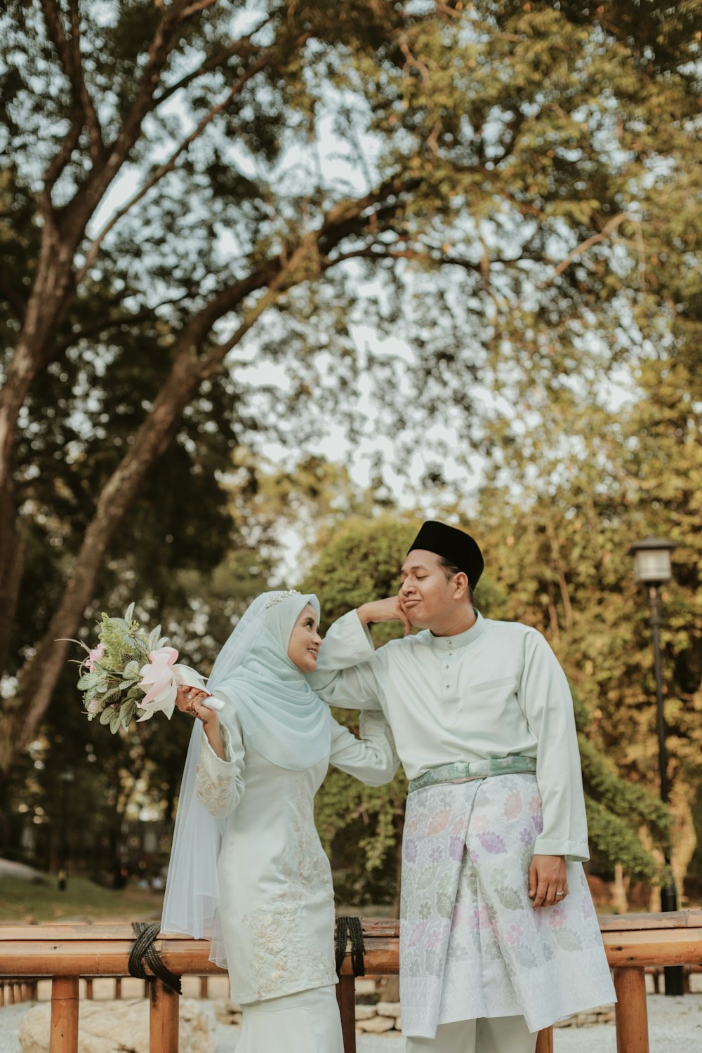 a man and woman posing for a picture under a tree