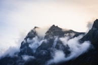 A mountain range with soft morning light and scattered clouds.