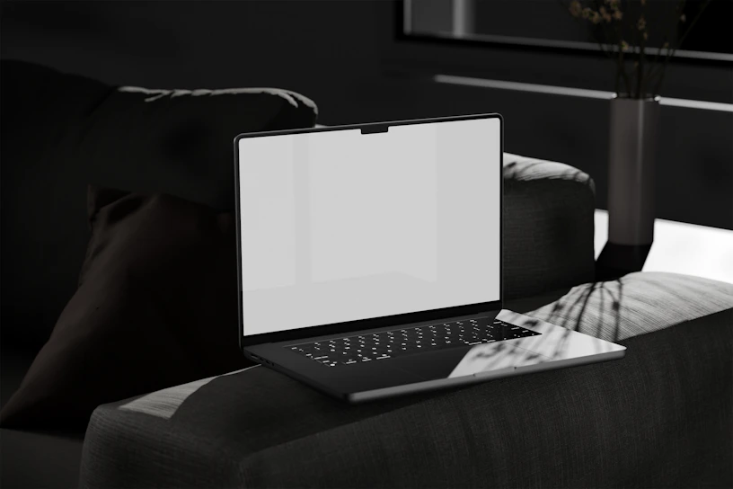 A sleek modern laptop on a dark desk with green and yellow ambient lighting