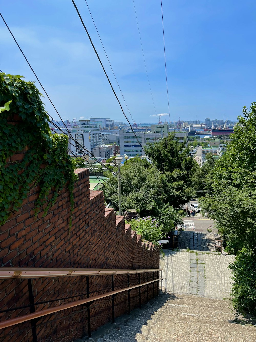 a brick wall with a fence and trees and a city in the background