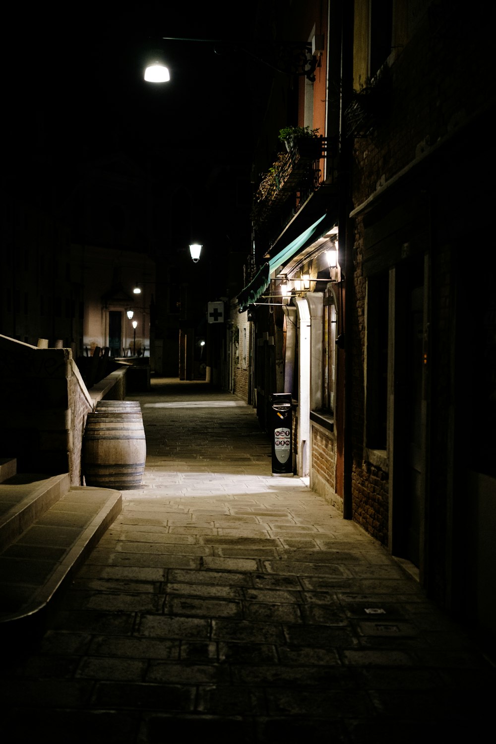 a stone walkway between buildings at night