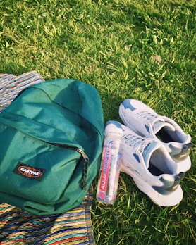 A casual backpack and cap laid out on a concrete bench with soft natural light.