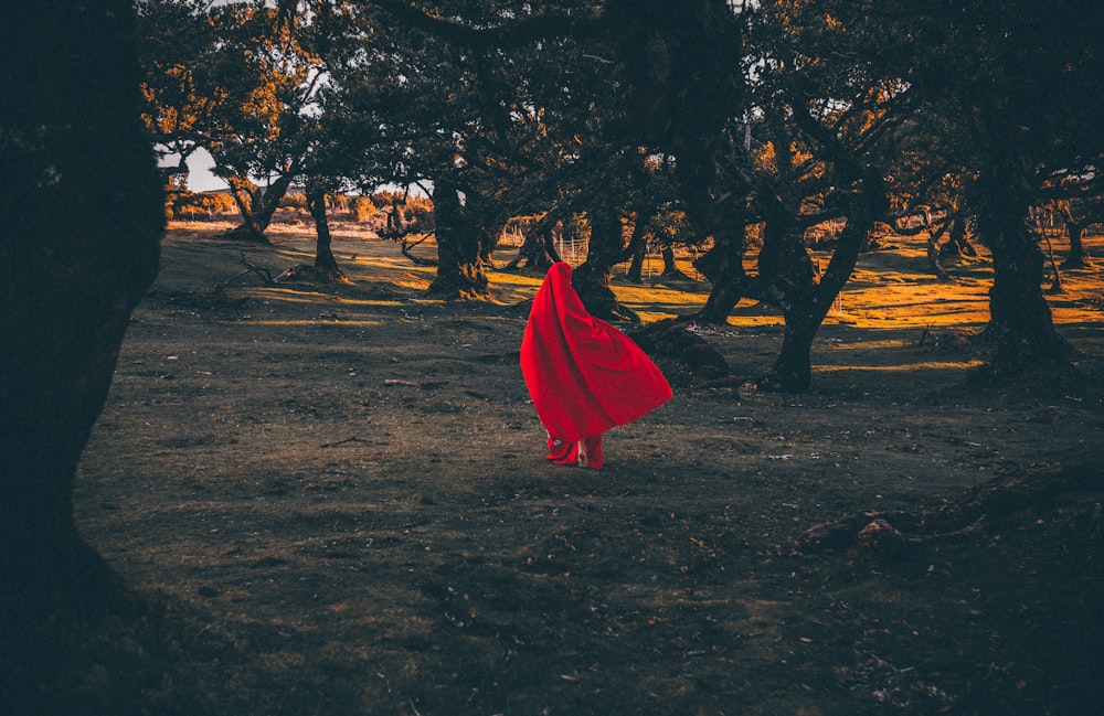 a person in a red dress sitting on the ground under a red umbrella