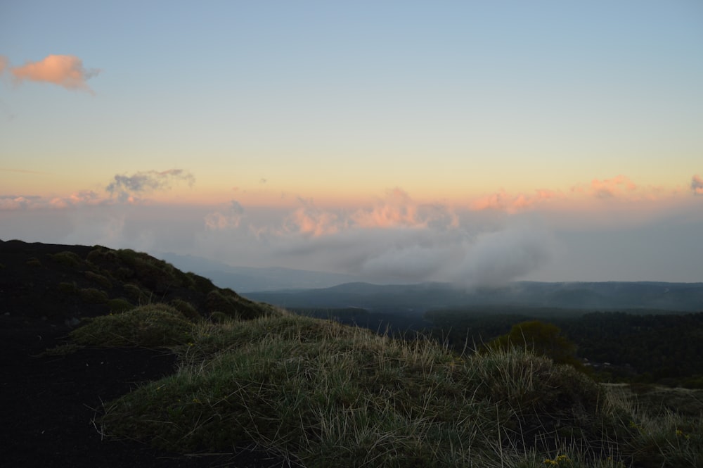 a grassy hill with a body of water in the distance