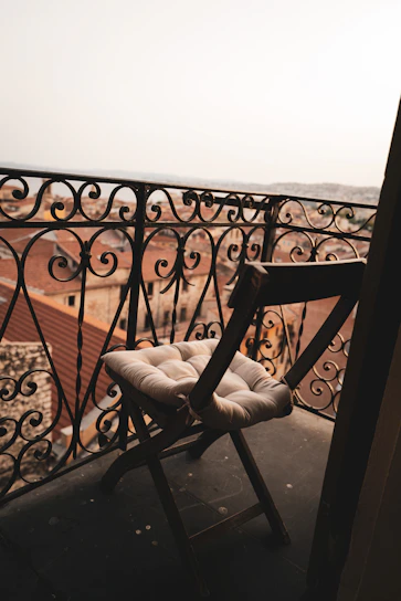 Swivel metal outdoor club chair with soft cushions on a sunny balcony.
