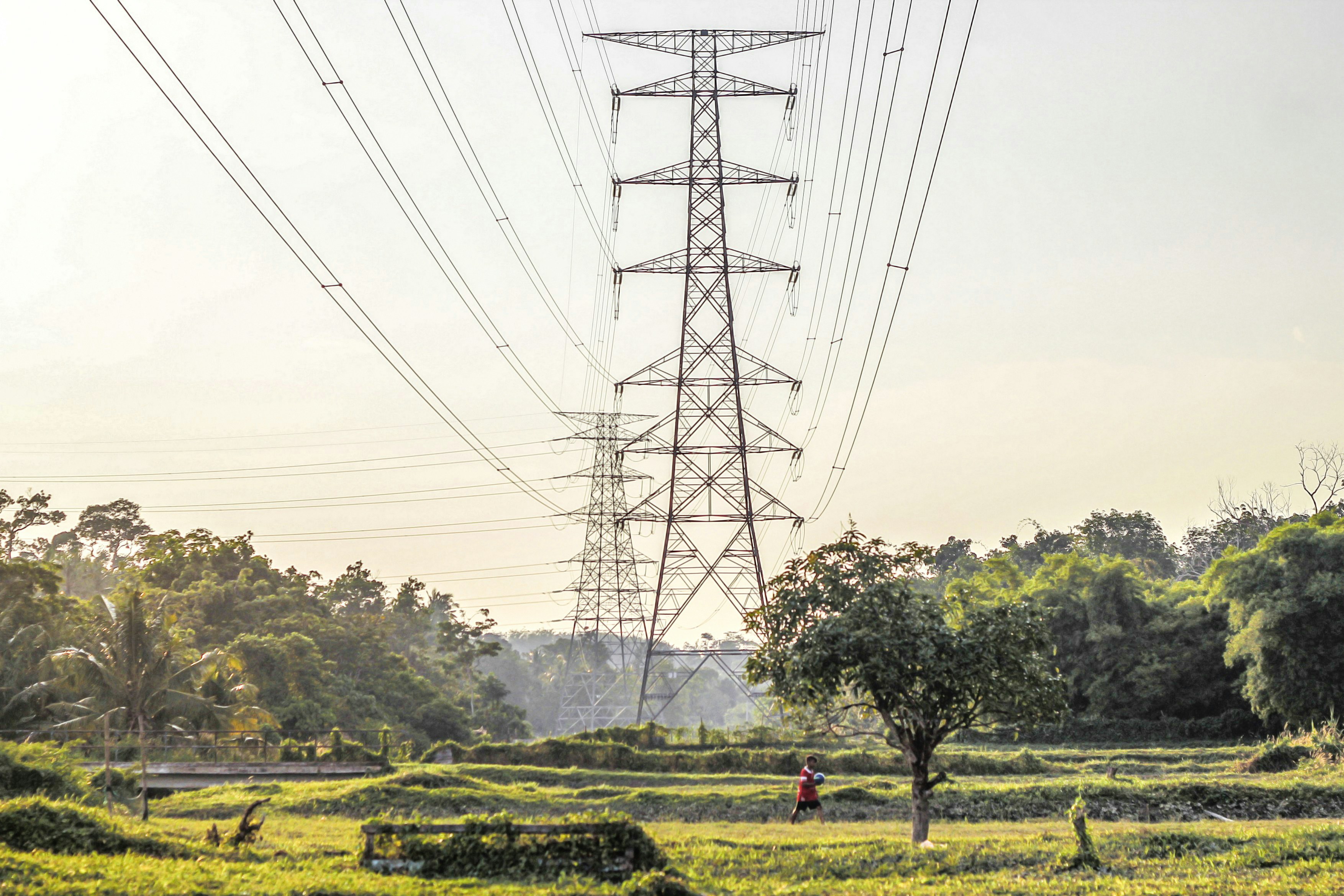 a person walking on a path near a power line with Moonlight tower in the background