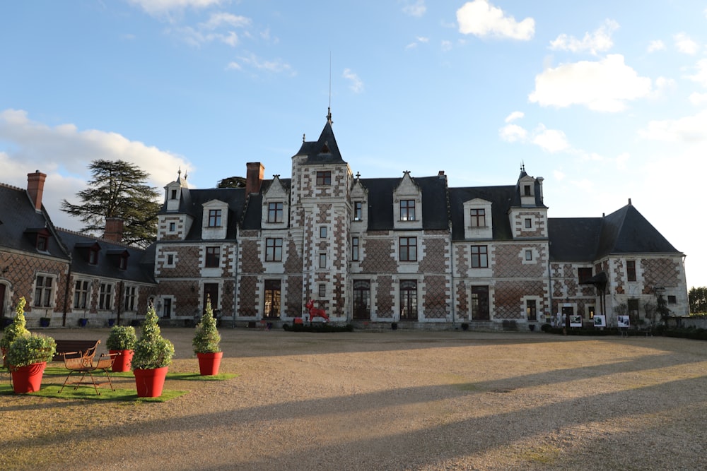 Une grande maison avec une pelouse et des tables devant elle