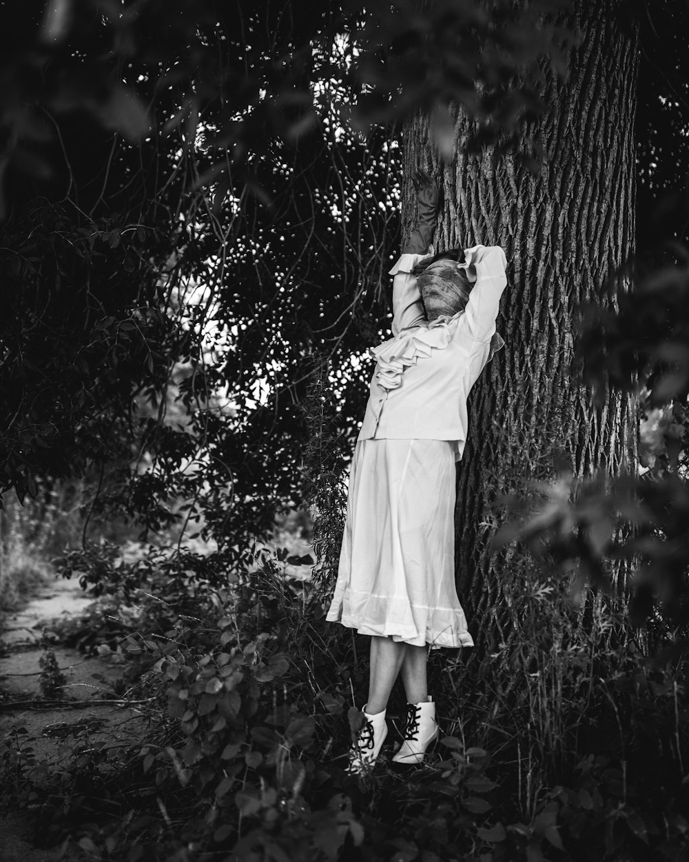 a girl in a dress standing in front of a forest