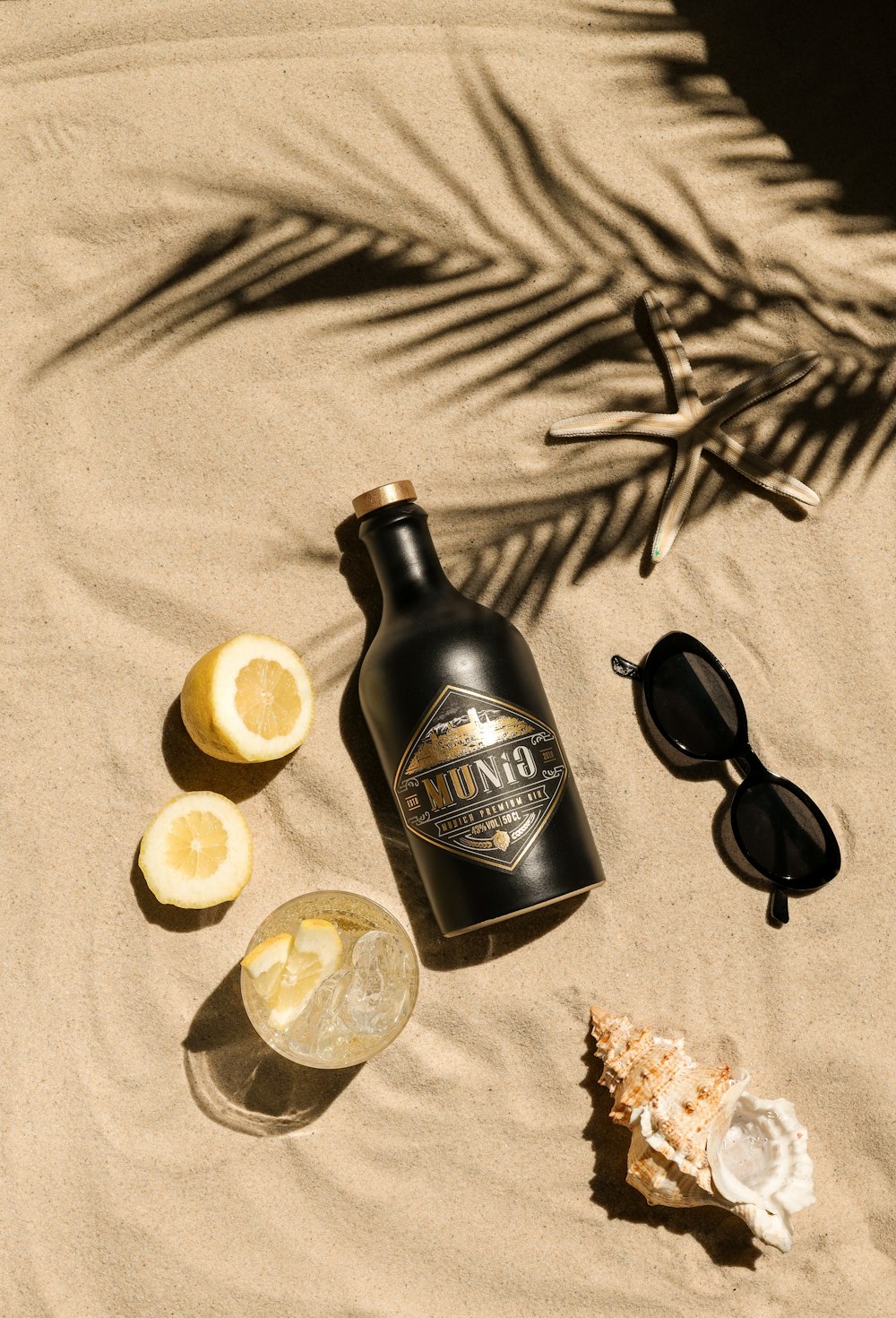 una botella de alcohol y gafas de sol sobre una manta