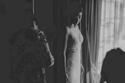 An intimate scene of a woman in elegant sleepwear standing by a window with sheer curtains.