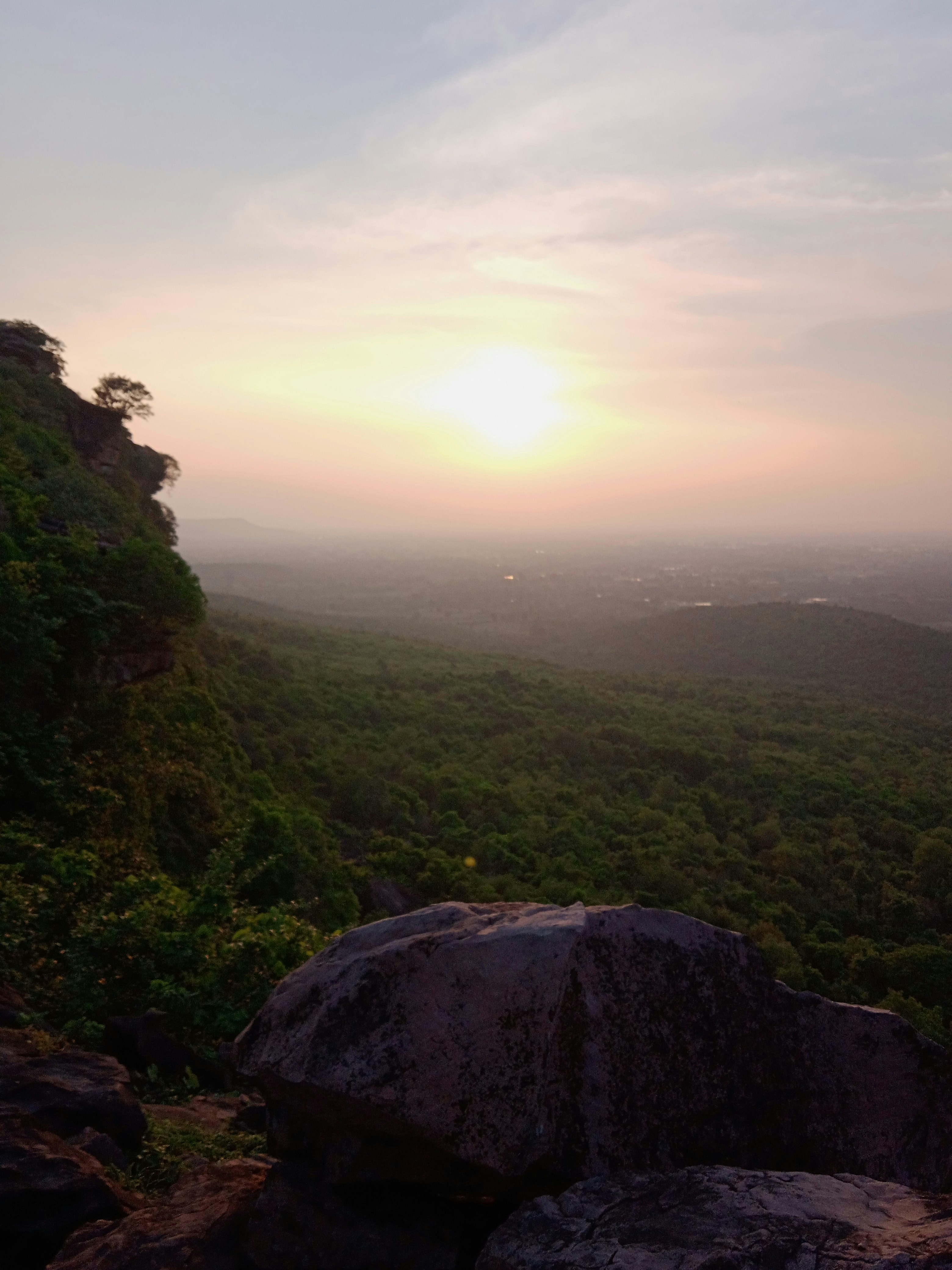 a view of a valley with trees and a sunset
