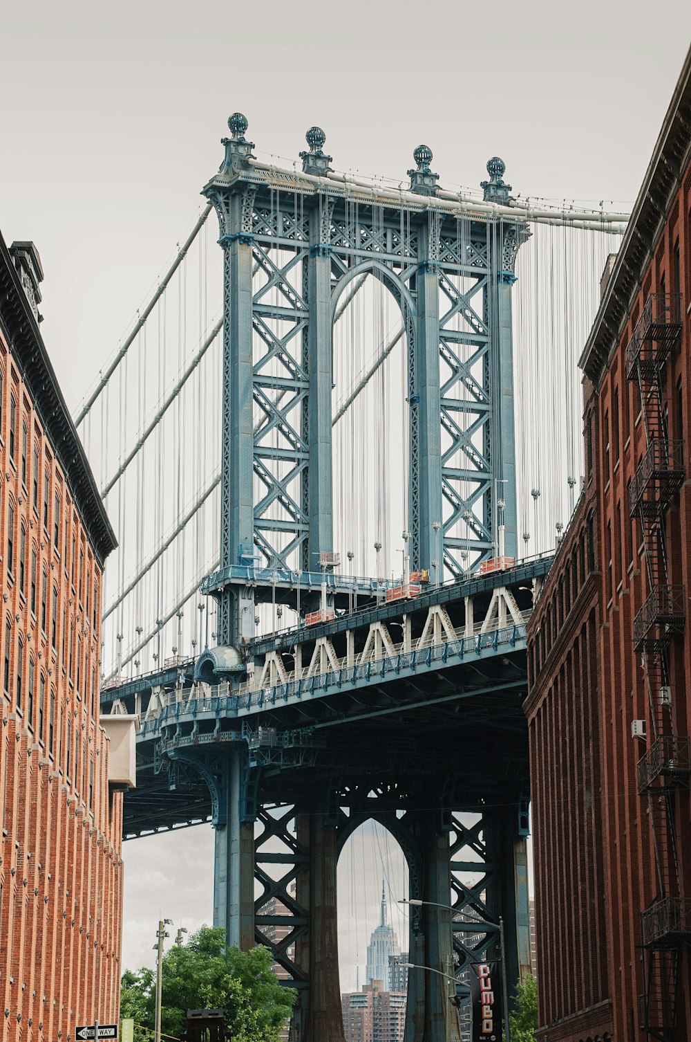 a large metal bridge with Manhattan Bridge in the background