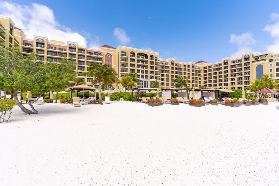 A stunning beachfront hotel with palm trees and clear blue skies.