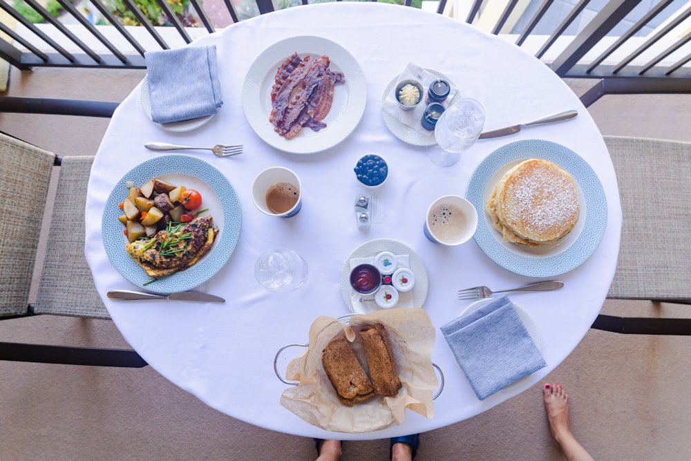 a table with plates of food and cups of coffee