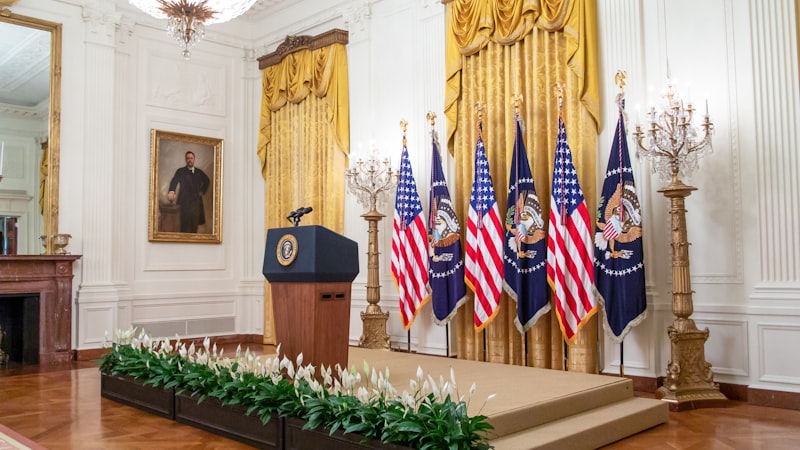 White House podium, U.S. presidential address, American flag, teleprompter, news conference room