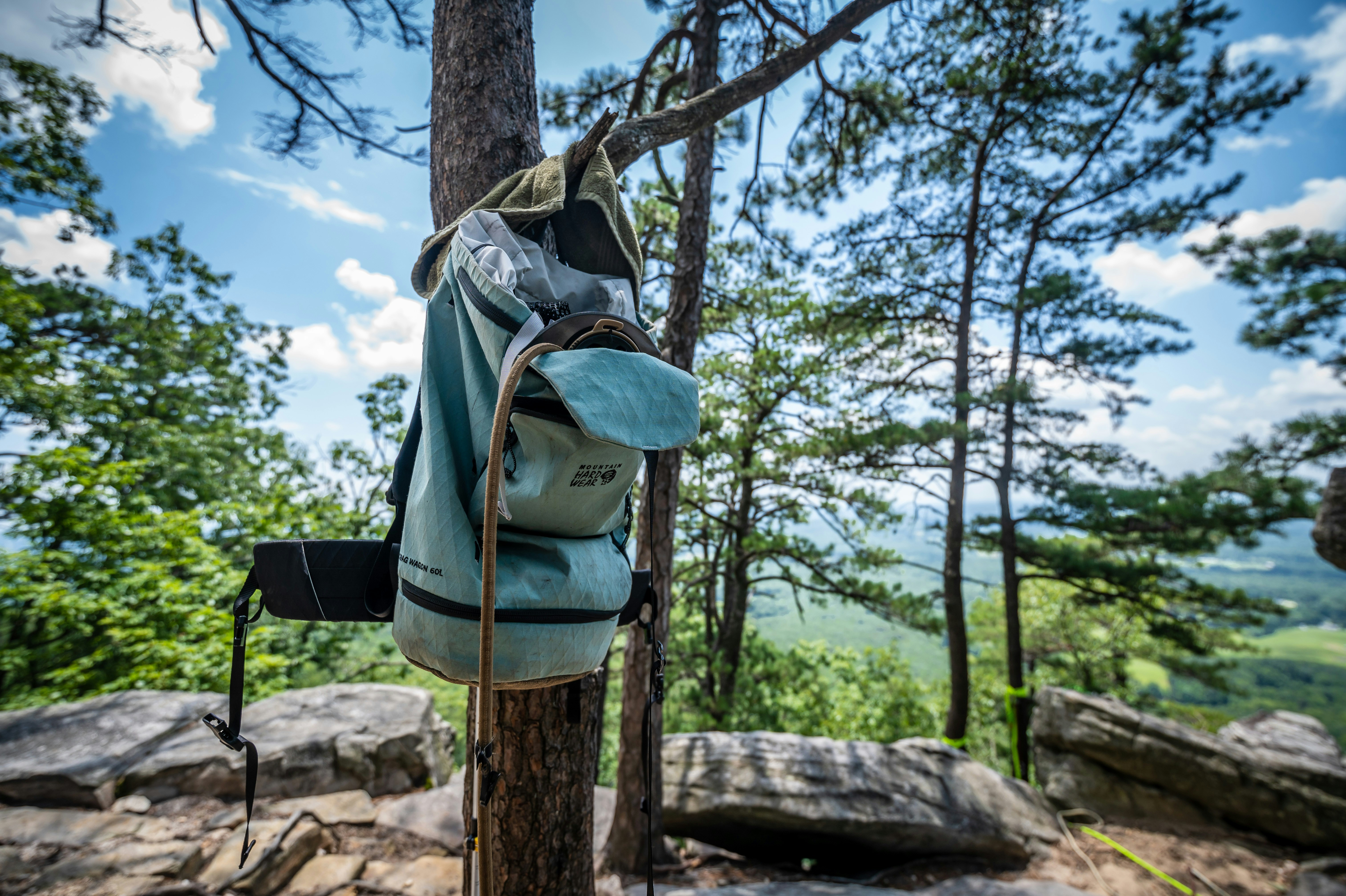 Rock climbing pack hanging on a tree overlooking a cliff rock climbing route. 