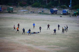 Corporate team engaged in an outdoor team-building activity on a grassy field surrounded by hills.