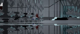 An abstract interior space with symmetrical geometric structures and mirrored surfaces. The design features sharp, angular elements with a modern aesthetic. A notable touch of red and blue hints at the presence of an abstract object or character nestled within the environment, creating a focal point amid the predominantly gray and black tones.