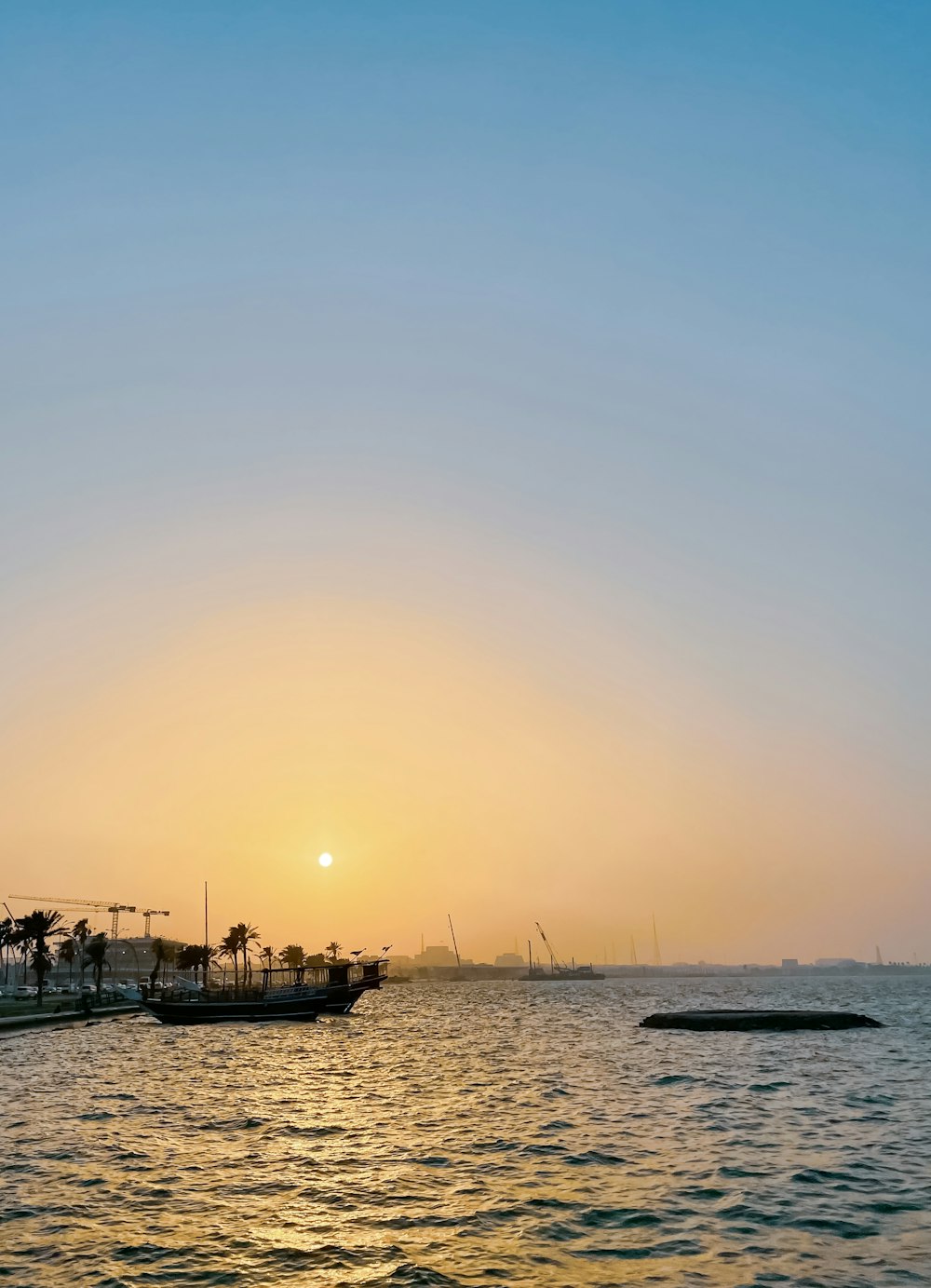 a body of water with boats in it and a sunset in the background