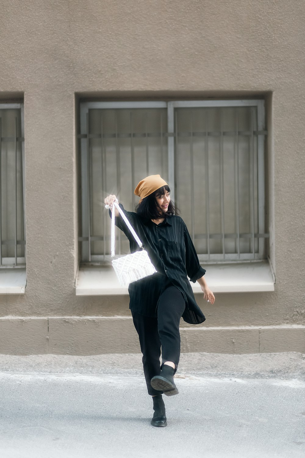 a man in a black coat and hat dancing outside