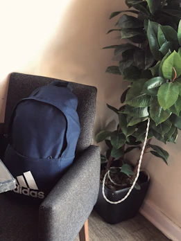 A stylish college backpack in navy blue with multiple compartments, hanging on a chair.