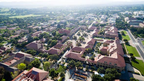 An aerial view of a sprawling university campus with green lawns and contemporary buildings.