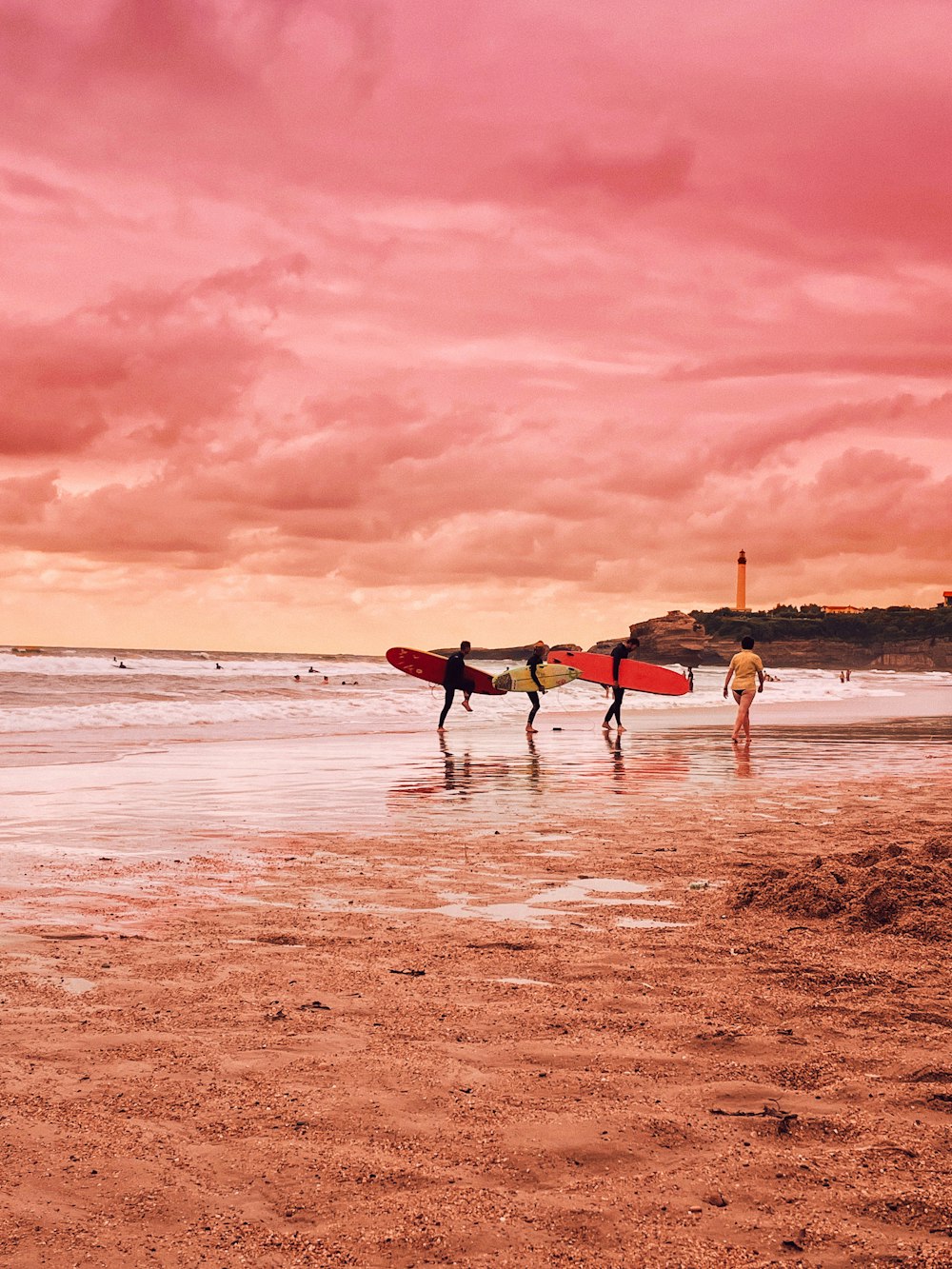 a couple of people carrying surfboards on a beach