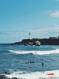Group of surfers catching waves at Taghazout beach under a clear blue sky
