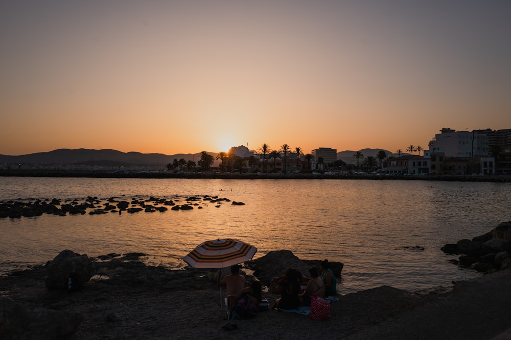 people sitting on a beach under an umbrella